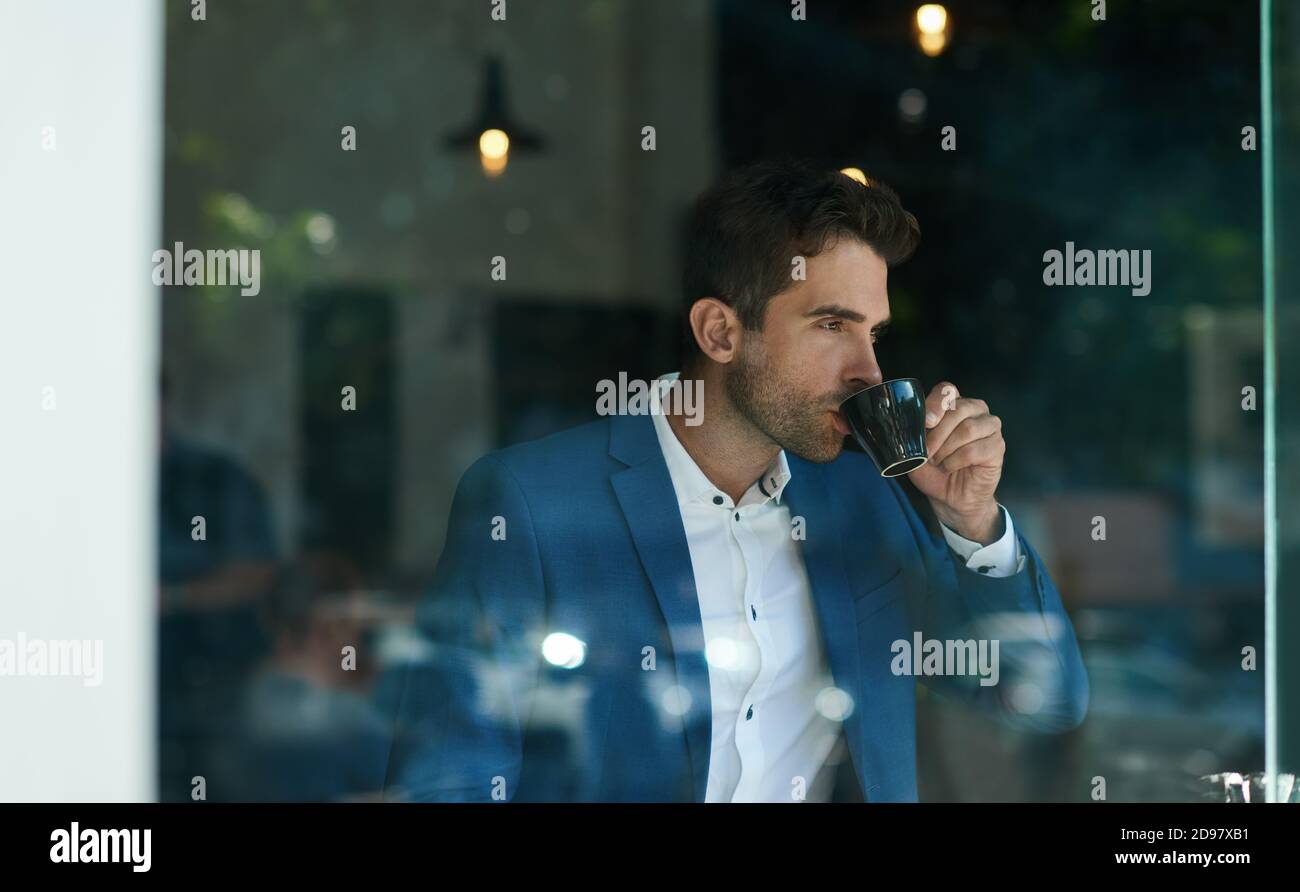 Uomo d'affari che beve una tazza di caffè all'interno di un caffè Foto Stock