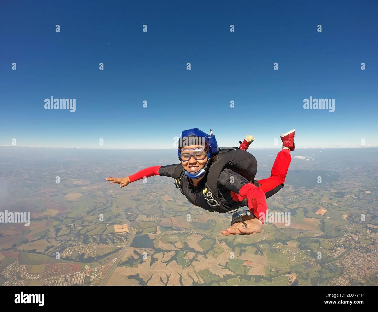 Donna nera sorridente che salta dal paracadute Foto Stock
