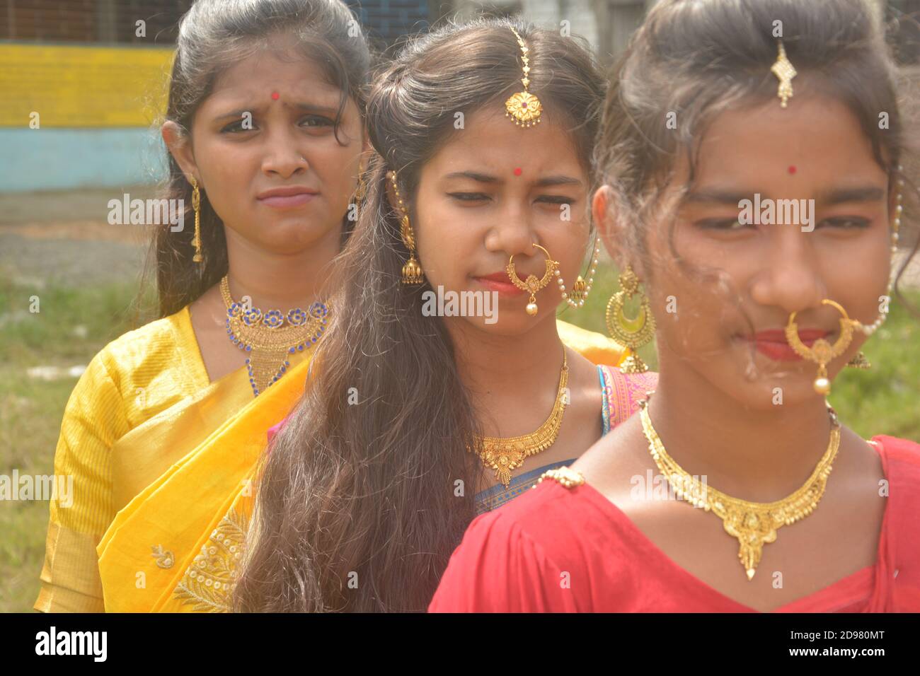 Primo piano di tre ragazze indiane adolescenti che indossano orecchini a collana con naso dorato sari maang tikka con make up, messa a fuoco selettiva Foto Stock