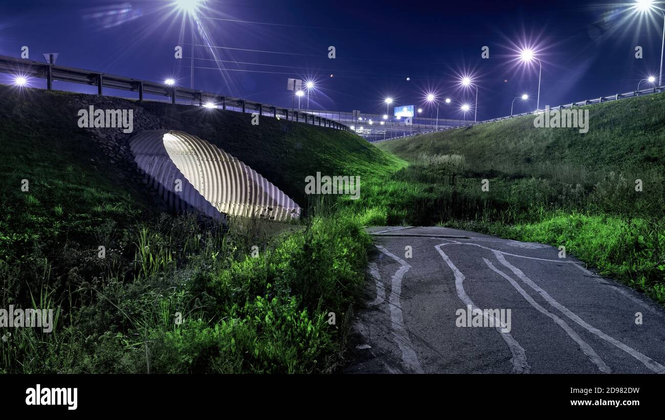 Tunnel illuminato sotto l'autostrada e luci notturne. Scena notturna di Noir Foto Stock