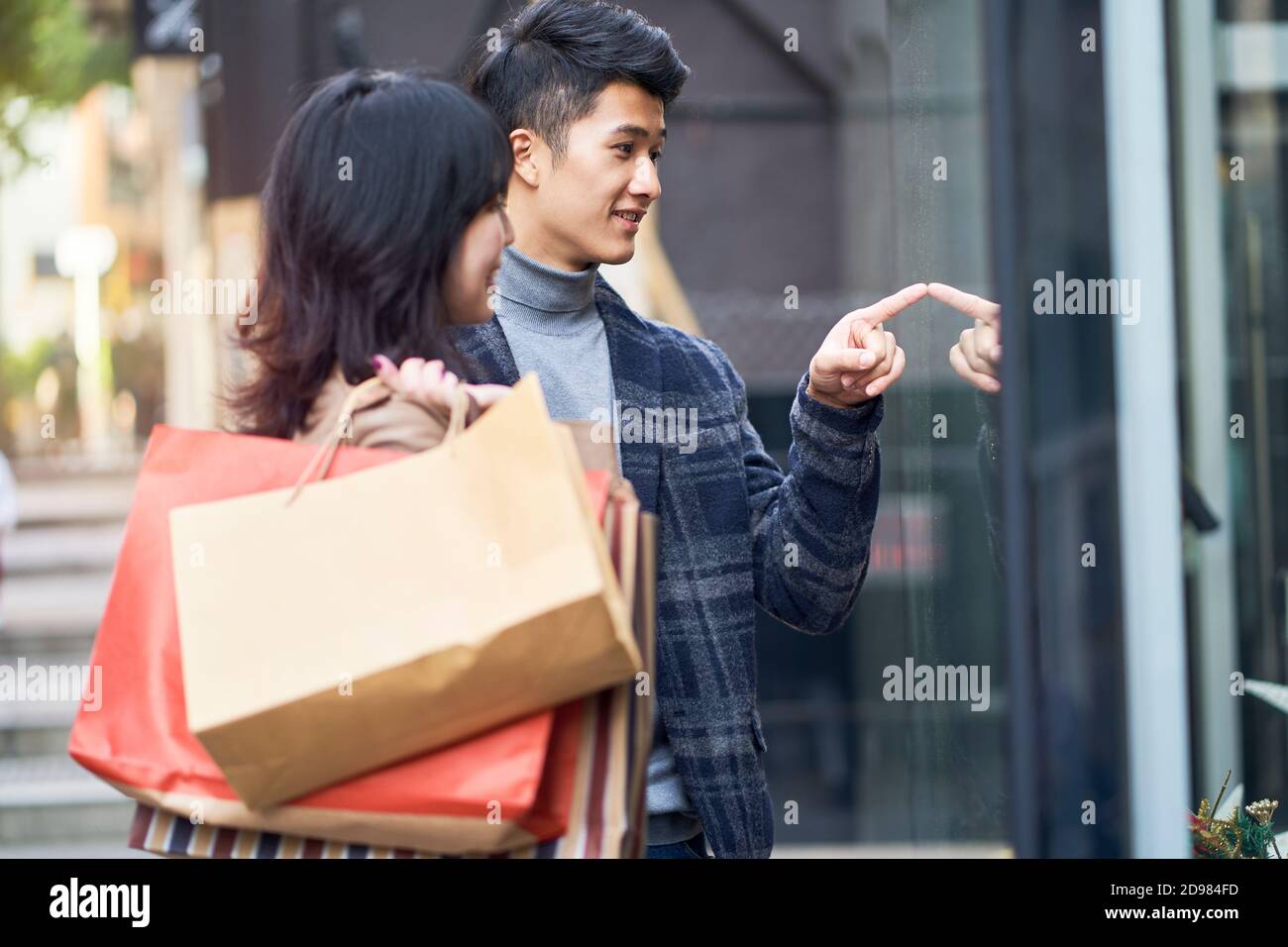 felice giovane coppia asiatica guardando in una vetrina mentre shopping nella città moderna Foto Stock