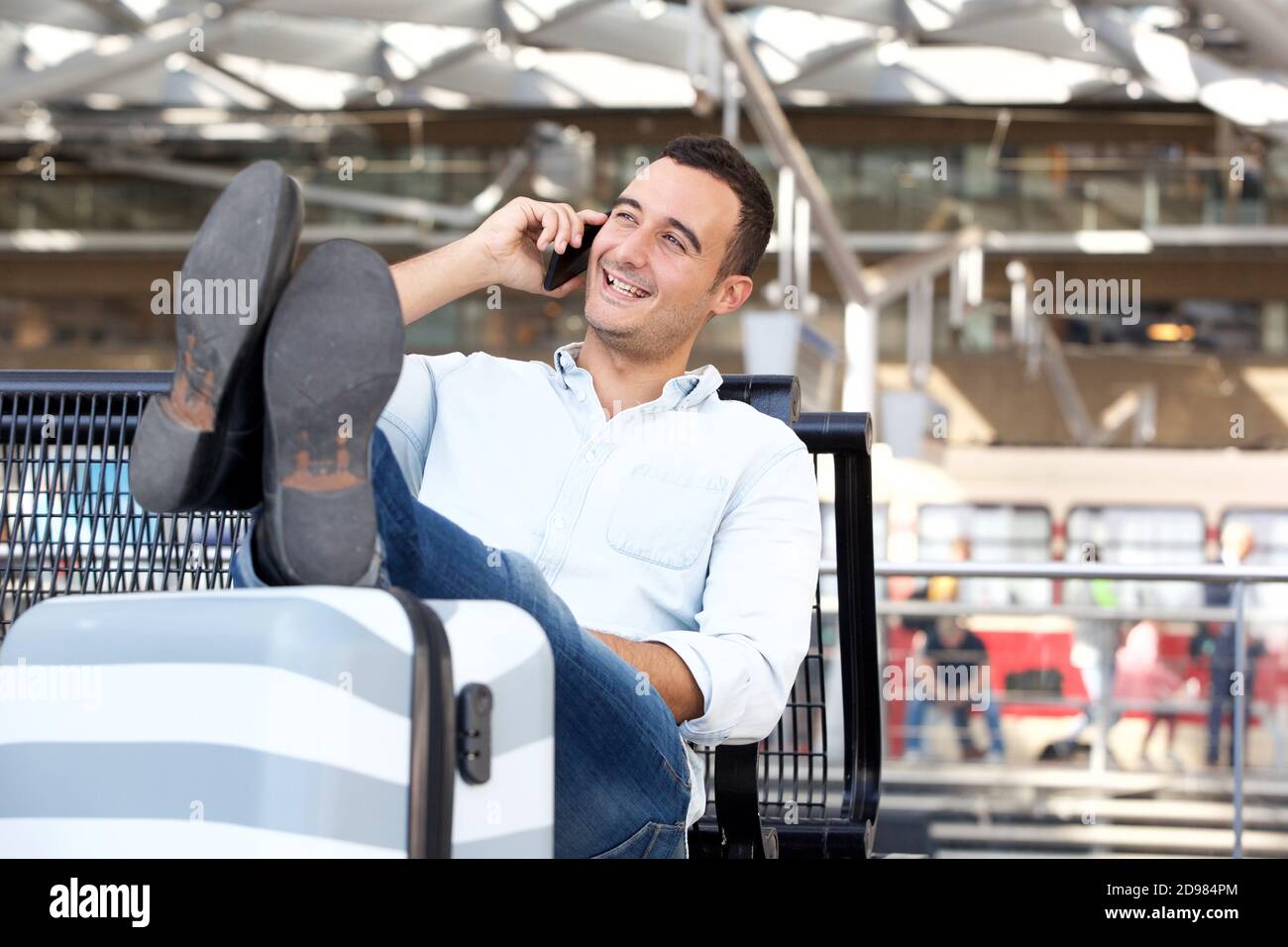 Ritratto di un uomo di viaggio rilassato che parla sul telefono cellulare a. stazione Foto Stock