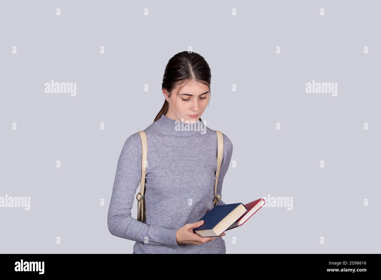 Ragazza studentesca disperata che tiene i libri che hanno ansia, sensazione di depressione di angoscia, seduta sola. Disordine nella testa, ansia e sensazione di mal di testa. Foto Stock