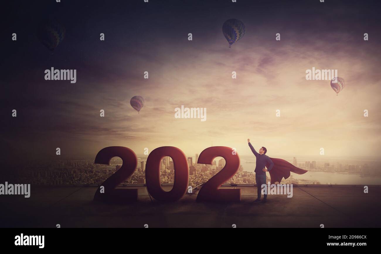 Uomo in attesa di successo seduti sul tetto di un grattacielo che si affaccia su un orizzonte di Città, 2020 numeri grandi che simboleggia il nuovo anno a venire. Trasognata guy Foto Stock