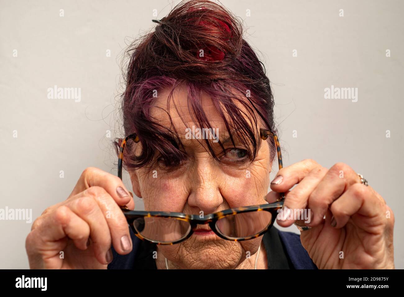 Lady nei suoi anni ottanta rimuovendo i suoi occhiali Foto Stock