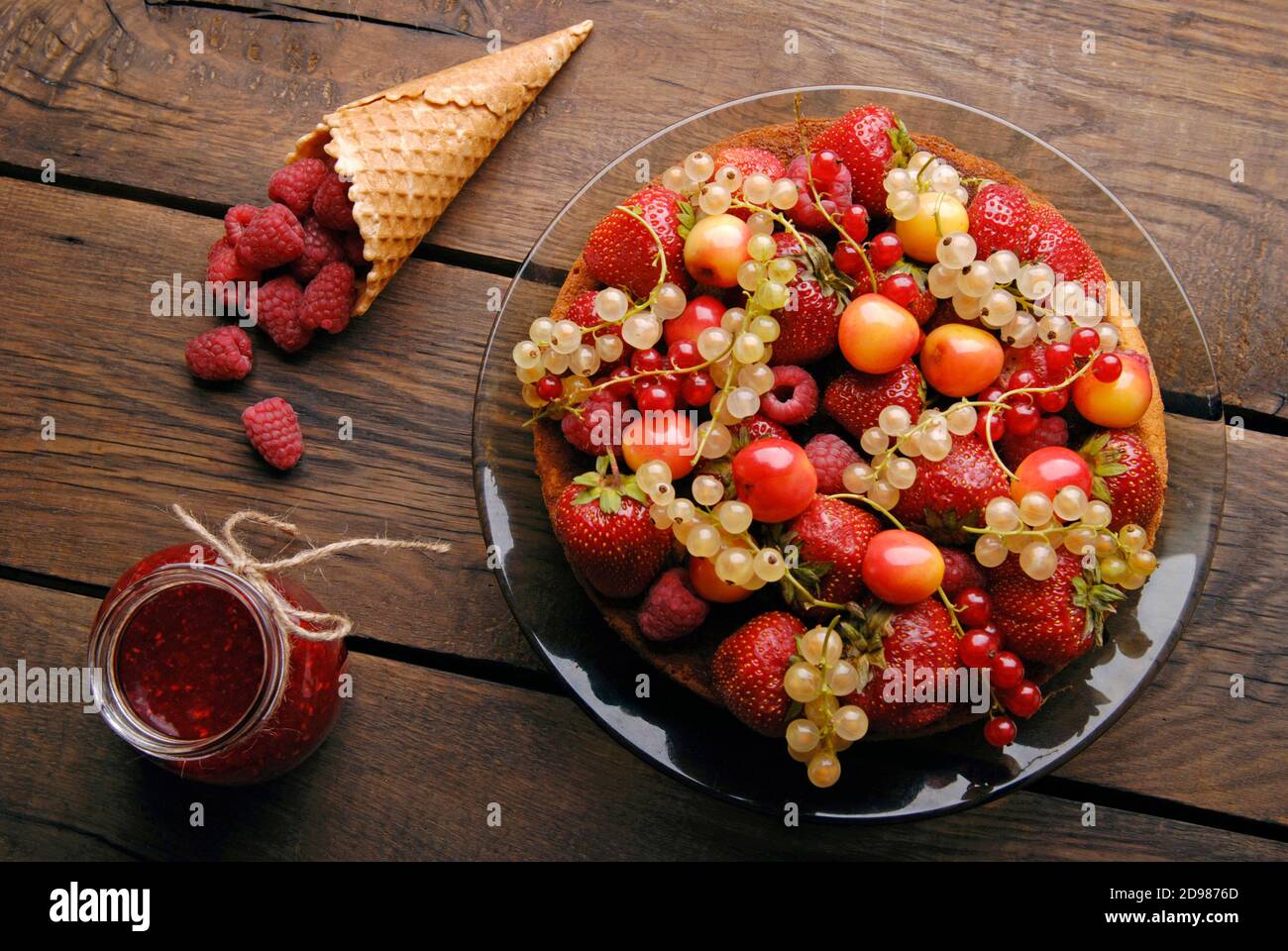 Pan di Spagna con diversi frutti estivi e lamponi in legno tabella Foto Stock