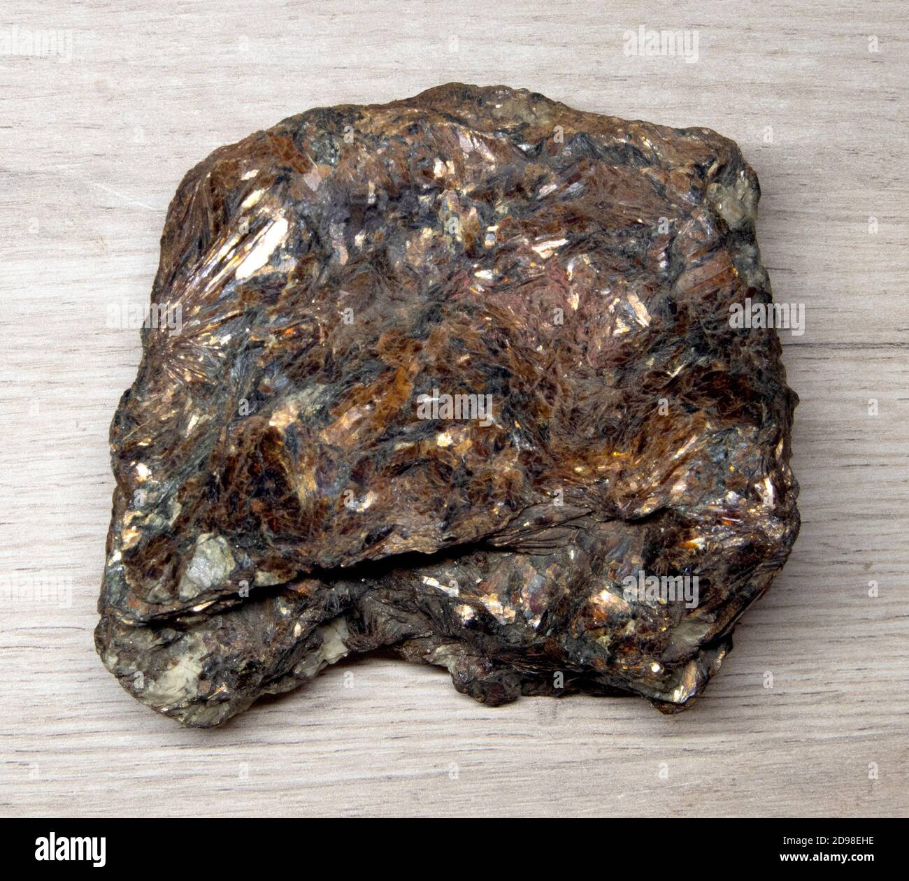 Grande pezzo di feldspar minerale sfaccettato lucido che giace su a. superficie in legno Foto Stock