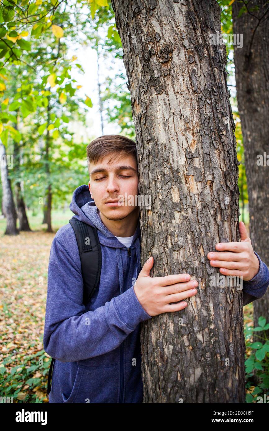 Il giovane abbraccio il tronco dell'albero nel Foresta Foto Stock