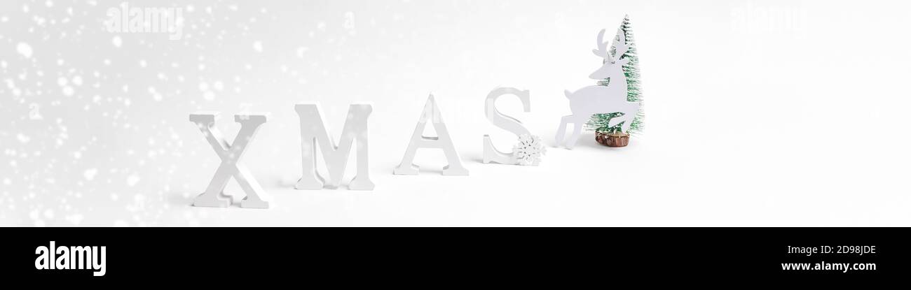 Natale festivo trendy minimo ampio banner bianco con decorazioni natalizie lettere XMAS, albero di Natale, cervo su bianco. Foto Stock