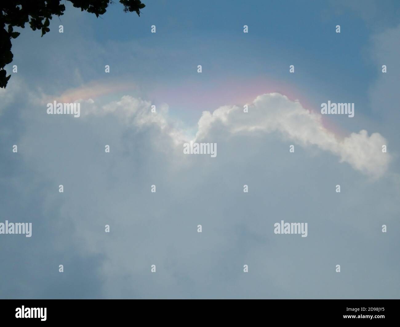 Spettro di colori su nuvole di pioggia bianche nel cielo blu Foto Stock