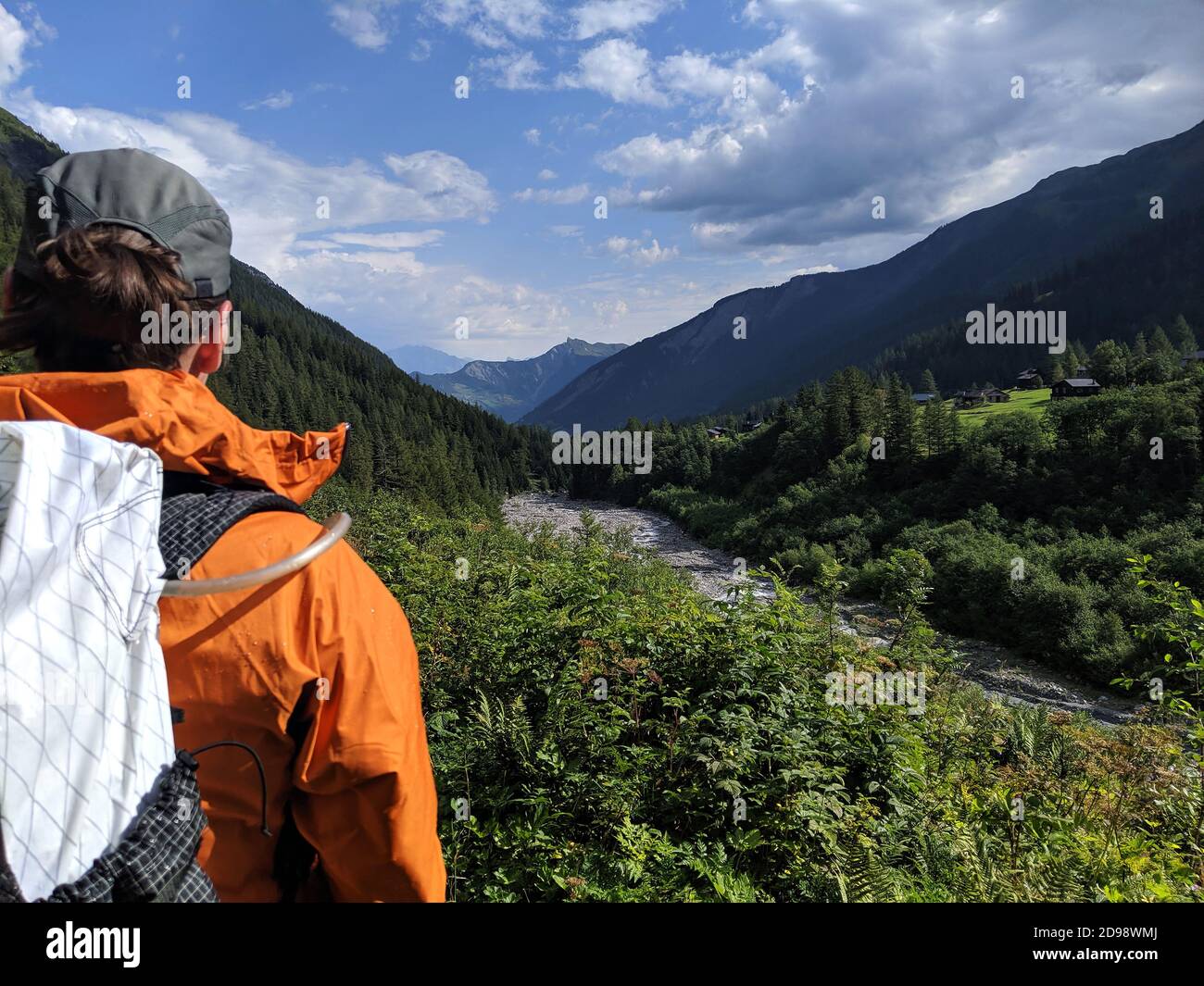 Donna escursionista ammirando la vista alpina durante il famoso percorso di trekking del Tour du Mont Blanc. Vista sul fiume circondato da boschi nelle Alpi. O Foto Stock