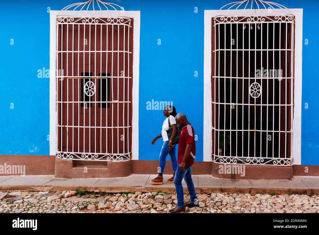 Una coppia afro-cubana cammina accanto a una casa in stile coloniale. Trinidad, Sancti Spíritus, Cuba, America Latina e Caraibi Foto Stock