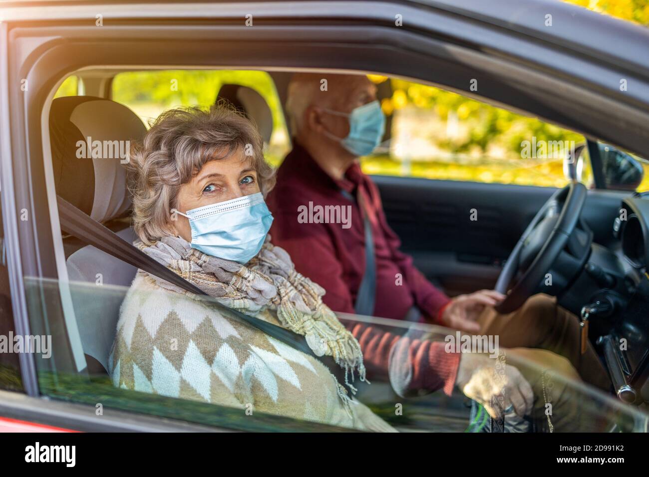 Coppia senior che indossa maschere di protezione per il viso in auto Foto Stock