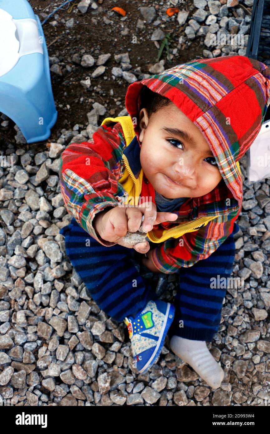 Un bambino guarda con impazienza senza sapere cosa regge il futuro. Skaramagas ospita un campo profughi "temporaneo", una sorta di sala d'attesa dove i migranti provenienti principalmente da Siria, Iraq e Afghanistan soggiornano prima di essere reinsediati altrove in Europa. A Skaramagas, possono anche sapere se la loro richiesta di trasferimento è stata approvata o respinta. Makariou, Skaramagkas, Grecia. Foto Stock