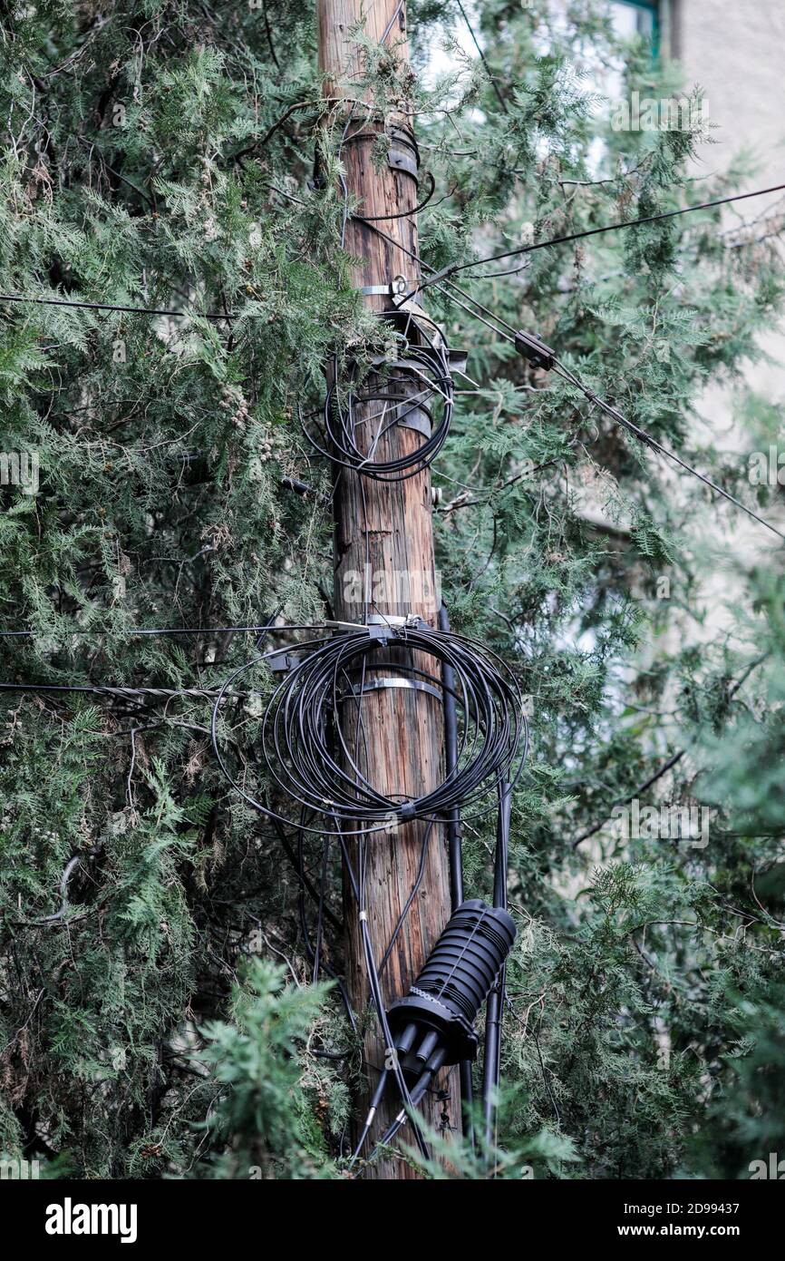 Molti cavi internet e TV non organizzati su un palo di legno a Bucarest. Foto Stock