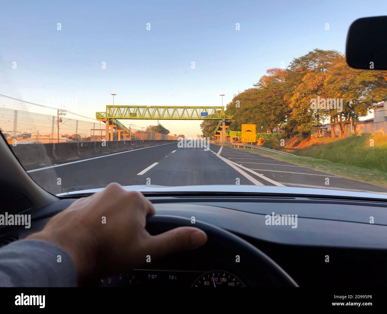 Un punto di vista del conducente all'alba, su un'autostrada con un passaggio pedonale. Foto Stock