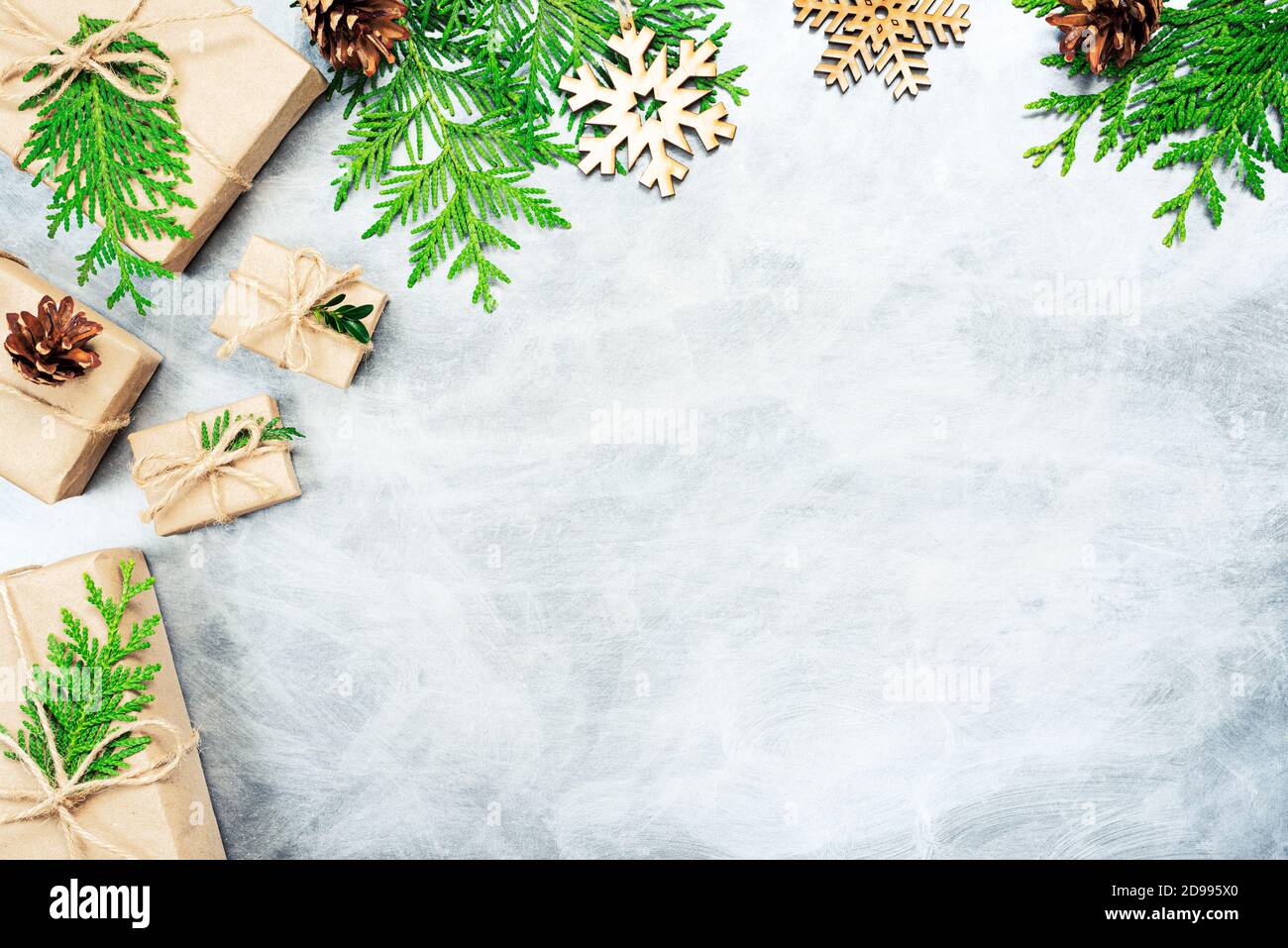 Composizione di Natale. Regali di Natale, coni di pino, rami di thuja e fiocchi di neve di legno. Vista dall'alto, disposizione piatta. Spazio di copia Foto Stock