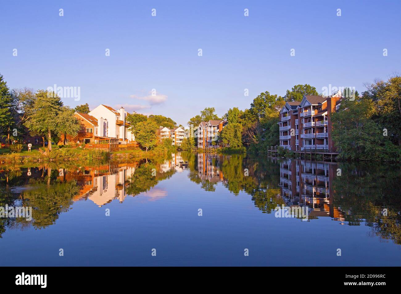 Quartiere suburbano di Washington DC all'inizio dell'autunno. Case con riflessione in uno stagno circondato da alberi e arbusti. Foto Stock