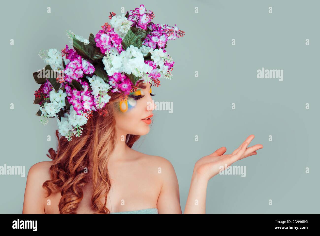 Ritratto primo piano bella giovane donna di profilo con lilla floreale archetto rivolto lateralmente con la mano, isolato su sfondo verde chiaro Foto Stock
