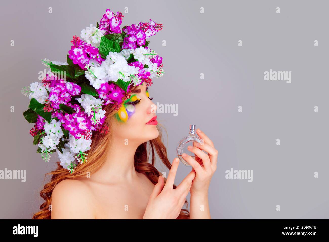 Closeup bella giovane donna nel profilo laterale con archetto lilla floreale odore di profumo - isolato su sfondo viola chiaro. H positivo Foto Stock