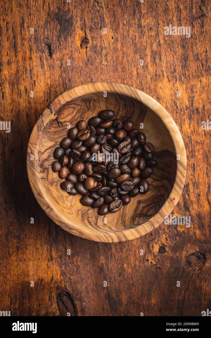 Chicchi di caffè tostati in una ciotola di legno su un tavolo di legno. Vista dall'alto. Foto Stock