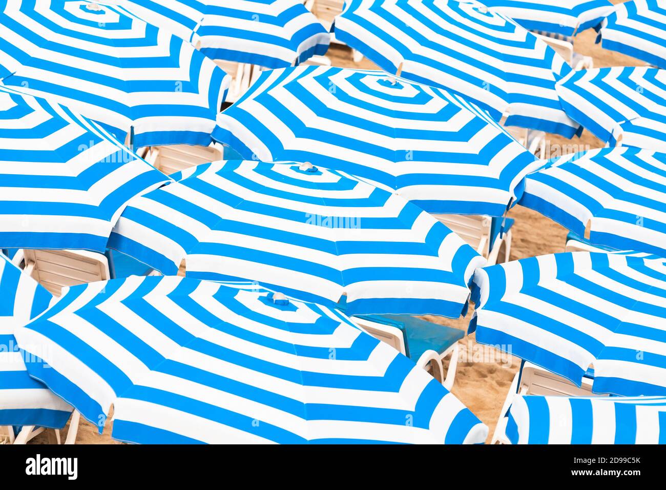 Ombrelli con motivo a strisce blu e bianco. Foto astratta di sfondo dell'estate scattata su una spiaggia in un giorno di sole Foto Stock