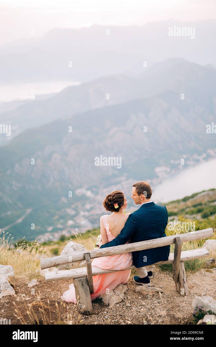 sposa e sposo seduti sulla panchina della montagna Sullo sfondo della Baia di Cattaro Foto Stock