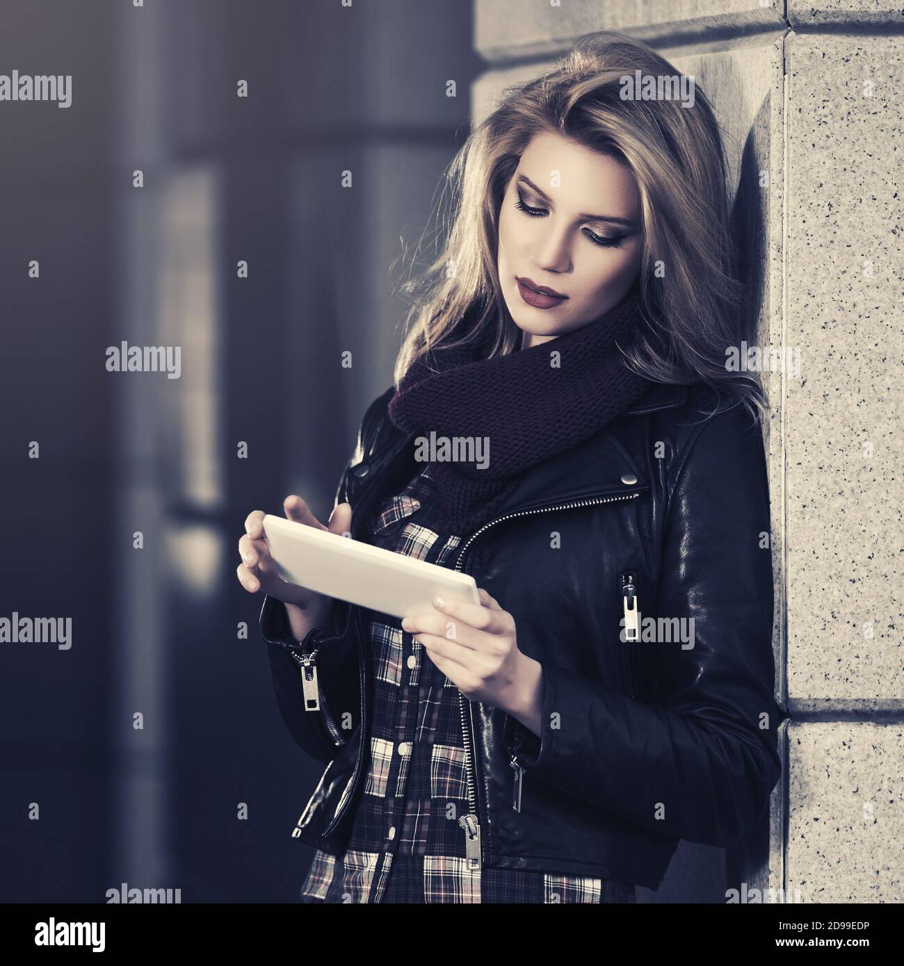 Giovane donna di moda che usa un computer tablet digitale sulla strada della città Elegante modello femminile con giacca in pelle nera Foto Stock