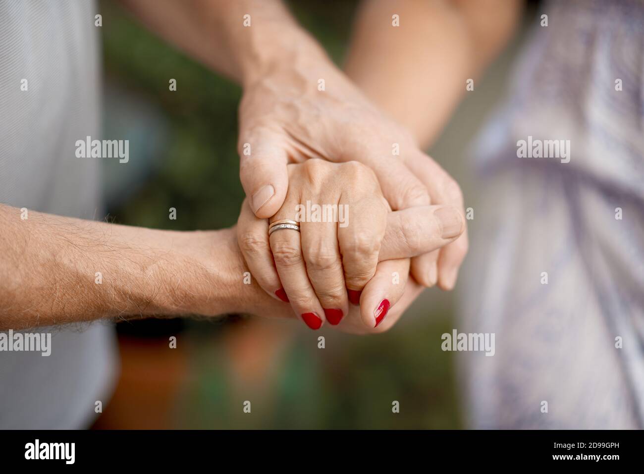 Ripresa ritagliata di una coppia senior che tiene le mani in un parcheggio Foto Stock
