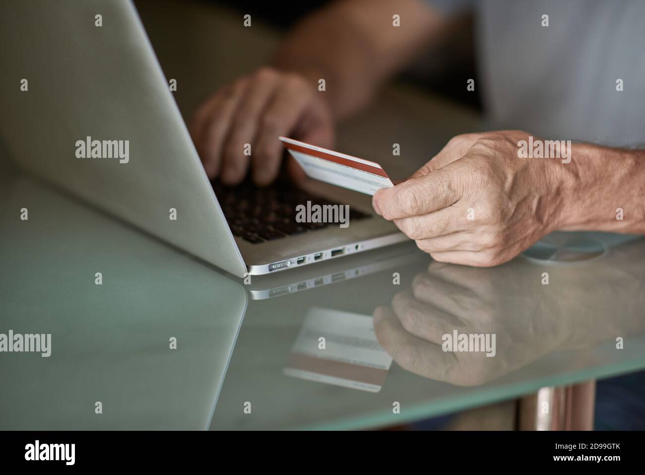 Uomo anziano che Shopping in linea con le carte di credito sul laptop a. tabella Foto Stock