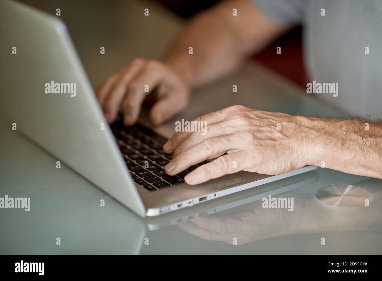 Il vecchio uomo che scrive a mano con il computer portatile in luce naturale Foto Stock