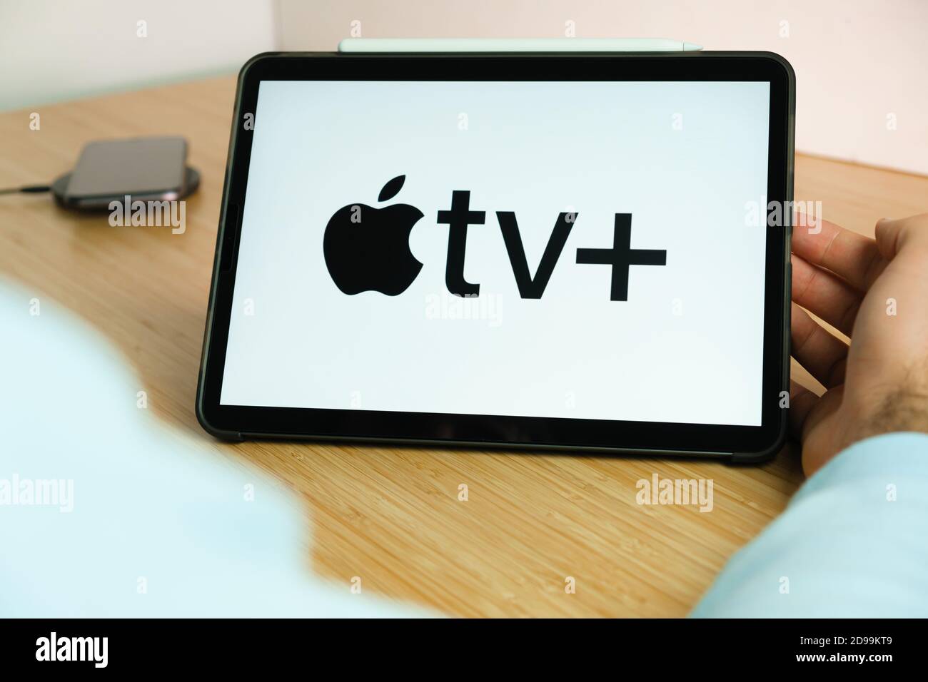Logo Apple TV+ sullo schermo del tablet iPad con smartphone di ricarica sul caricabatterie wireless sul tavolo in legno, novembre 2020, San Francisco Foto Stock