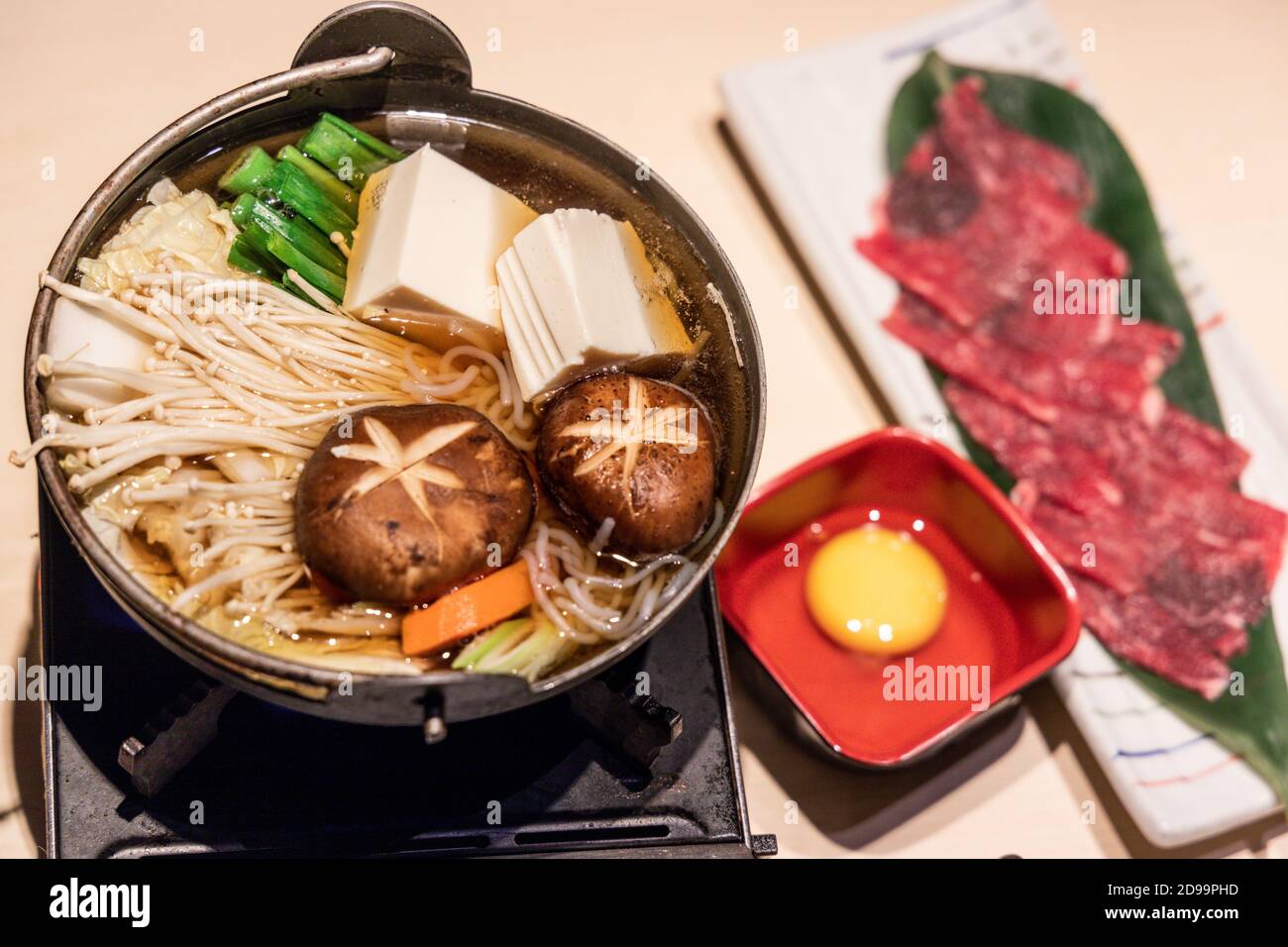 Pentola giapponese di sukiyaki con verdure, fette di manzo, uova crude Foto Stock