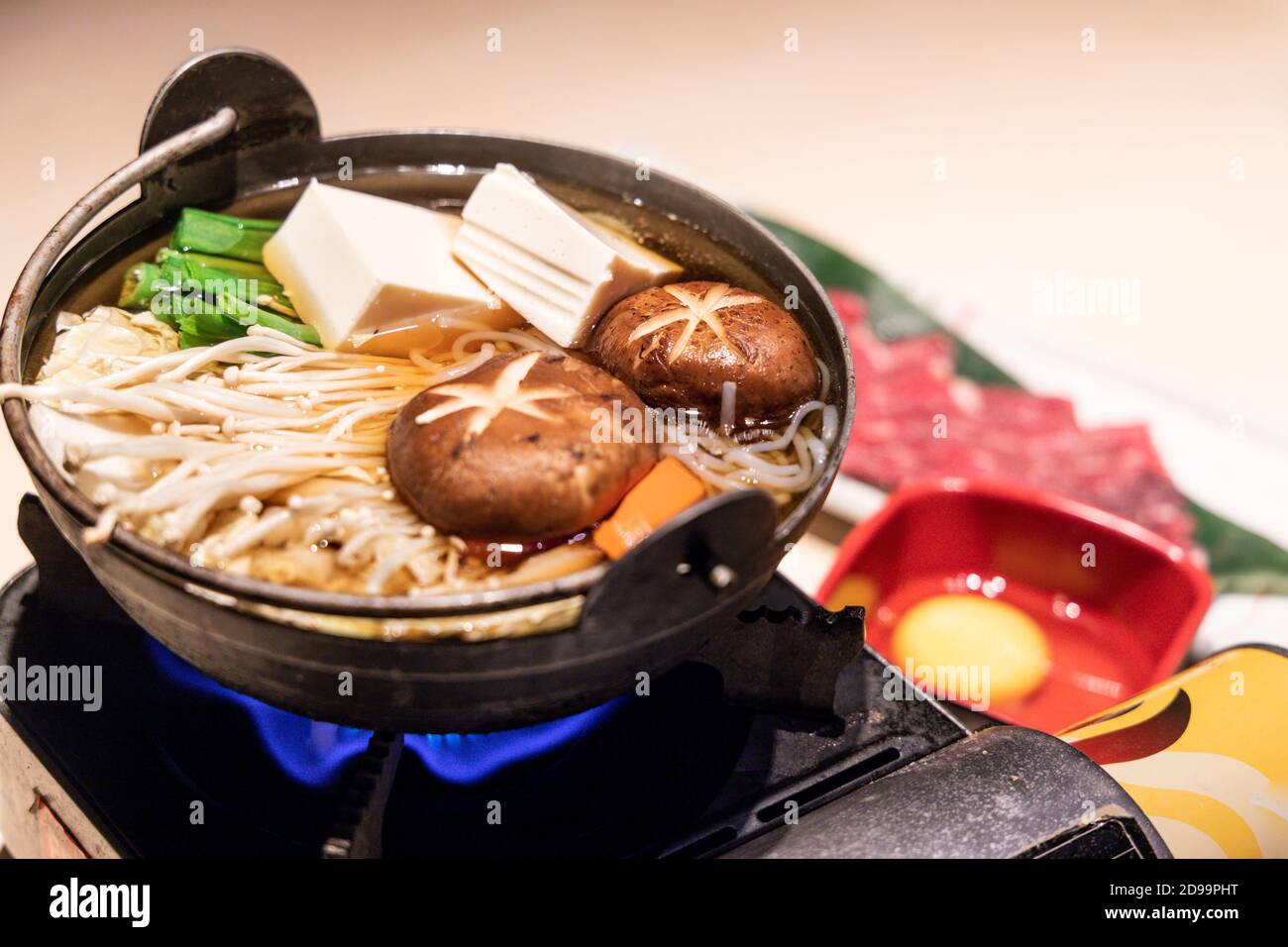 Pentola giapponese di sukiyaki con verdure, fette di manzo, uova crude Foto Stock