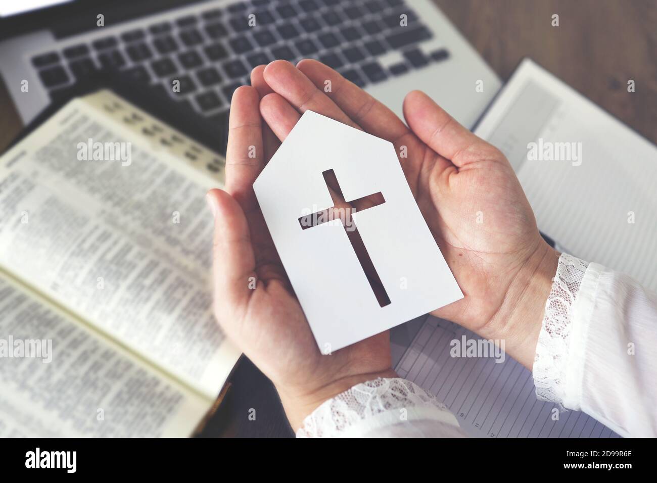 Donna che tiene carta chiesa icona pregare per fede con computer portatile, servizi della Chiesa online concetto, Online chiesa a casa concetto, spiritualità e. Foto Stock