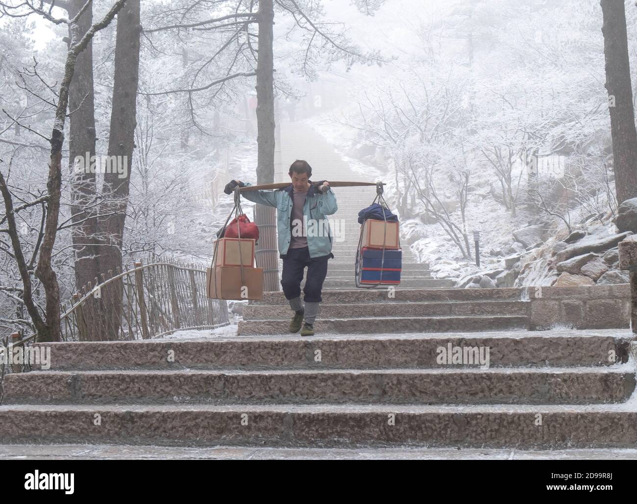 HUANGSHAN , ANHUI / CINA: GENNAIO 19 2020: L'uomo lavoratore che porta alimenti o zaino in spalla per il turismo che escursioni al picco. Foto Stock