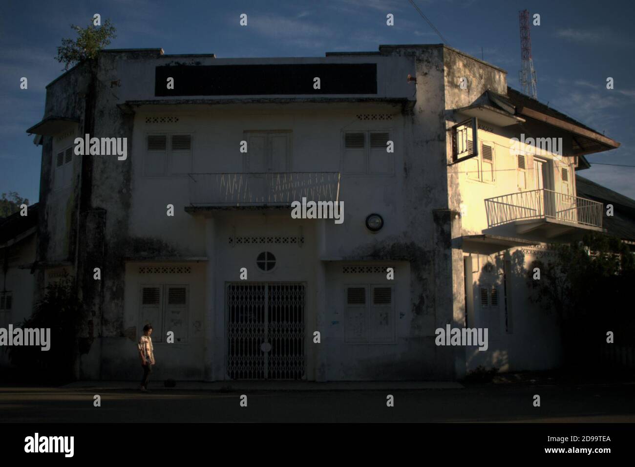 Cittadino che cammina su una strada vuota decorata da edifici con vecchio stile architettonico a Sibolga, una città si trova sulla costa occidentale di Sumatra, nella provincia di Sumatra del Nord, Indonesia. Foto Stock