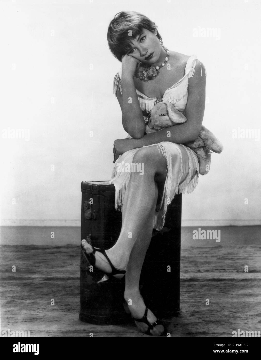 1960 , USA : l'attrice e ballerino cinematografico hollywoodiano SHIRLEY MacLaine ( nato nel 1934 ) NelL'APPARTAMENTO di Billy Wilder - FILM - CINEMA - FILM - ritratto - ritratto - danza - danza - cantante - attrice - MAC LAINE - Mc Laine - McLaine - collana - collana - gioco - posa leggy - peluche - orsacchiotto - frangia Frange - frange - frangia - noia - annoiato - annoiata - noia - tedium - annoiato - sandali - sandali - ballerina --- Archivio GBB Foto Stock