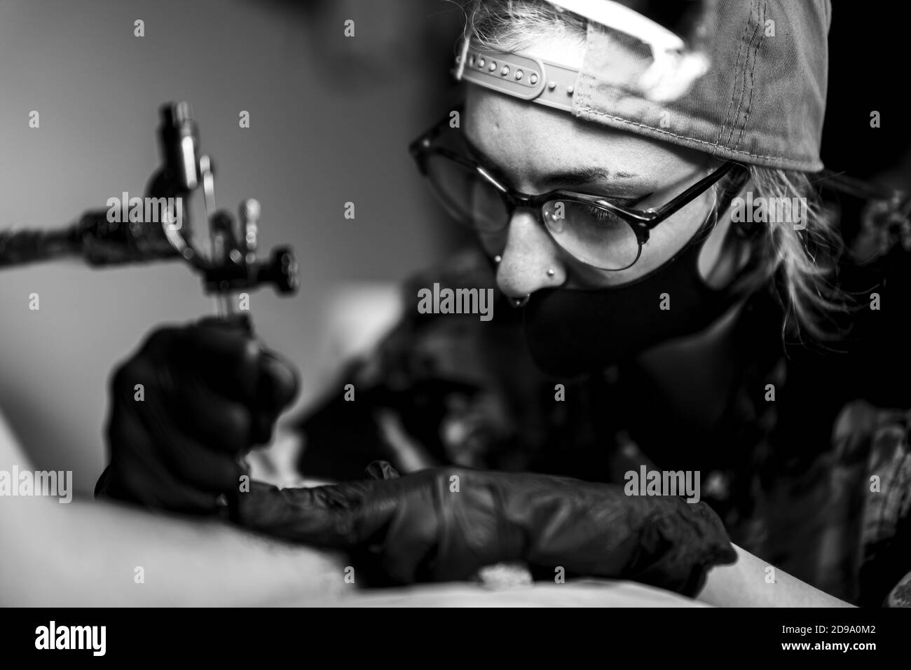 Tatuaggio artista con la macchina in mano si sta preparando a disegnare  nuovi tattoo nero sul client del braccio. Salone di tatuaggi. In bianco e  nero Foto stock - Alamy