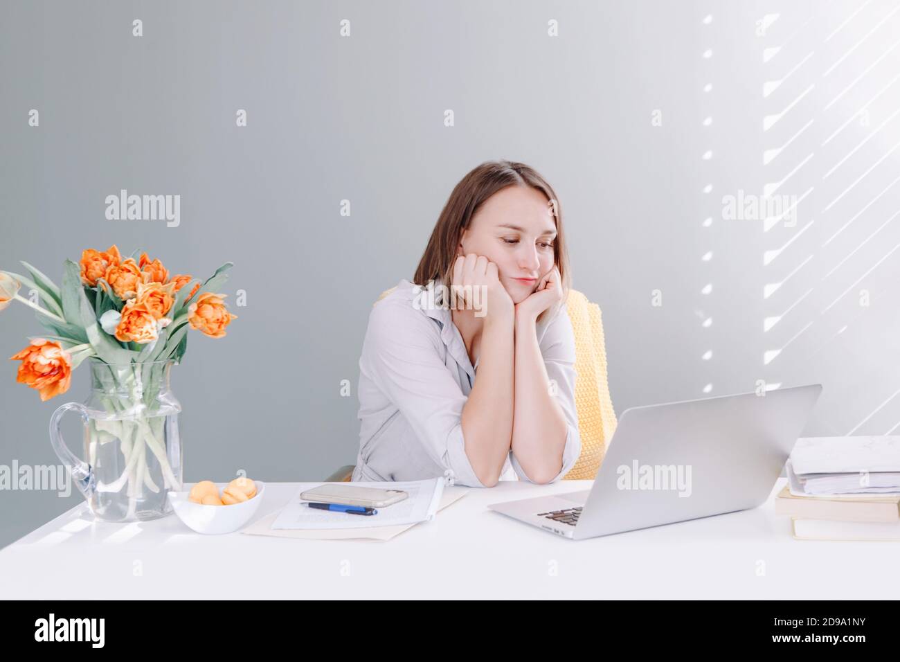 Annoiata donna di mezza età seduto al tavolo da tavolo che lavora su un computer portatile. Stanca giovane donna che impara online su Internet. Lavoro da casa. Re Foto Stock