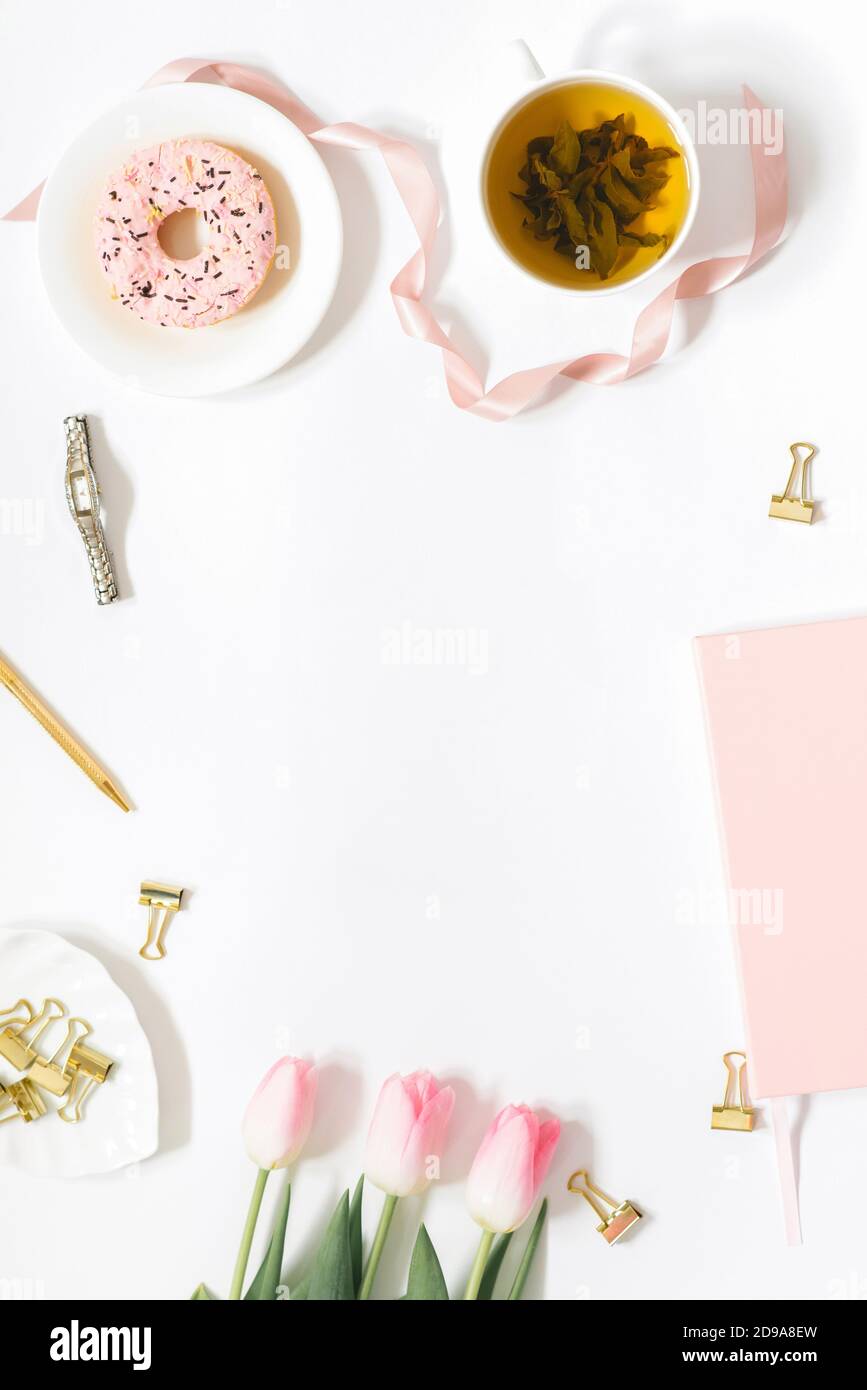 Delicato andamento feminista piatto con spazio per la copia. Ufficio, un bouquet di fiori, una tazza di tè e dolci su un piatto Foto Stock