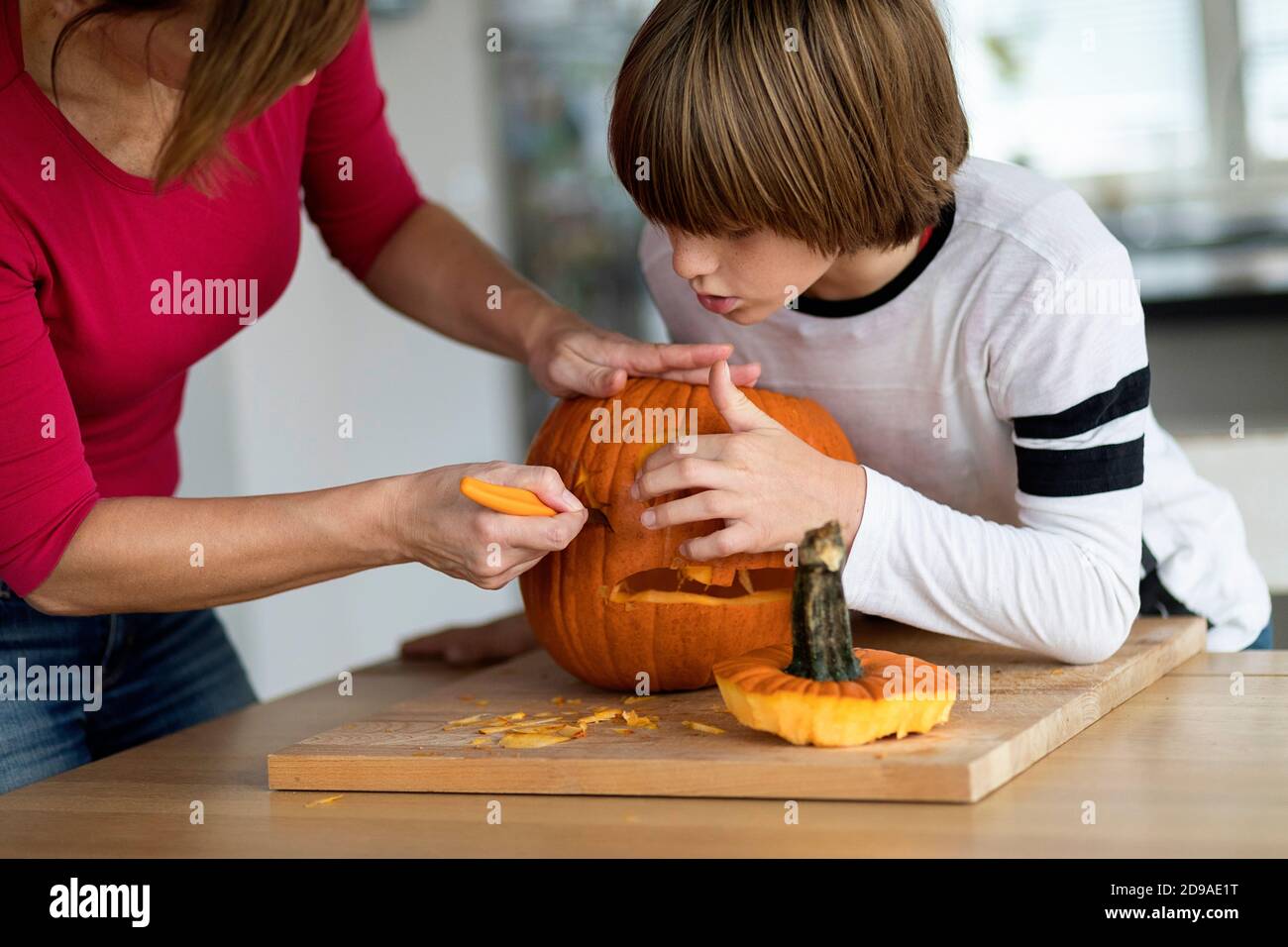 Madre e figlio intagliano zucca di Halloween in soggiorno Foto Stock