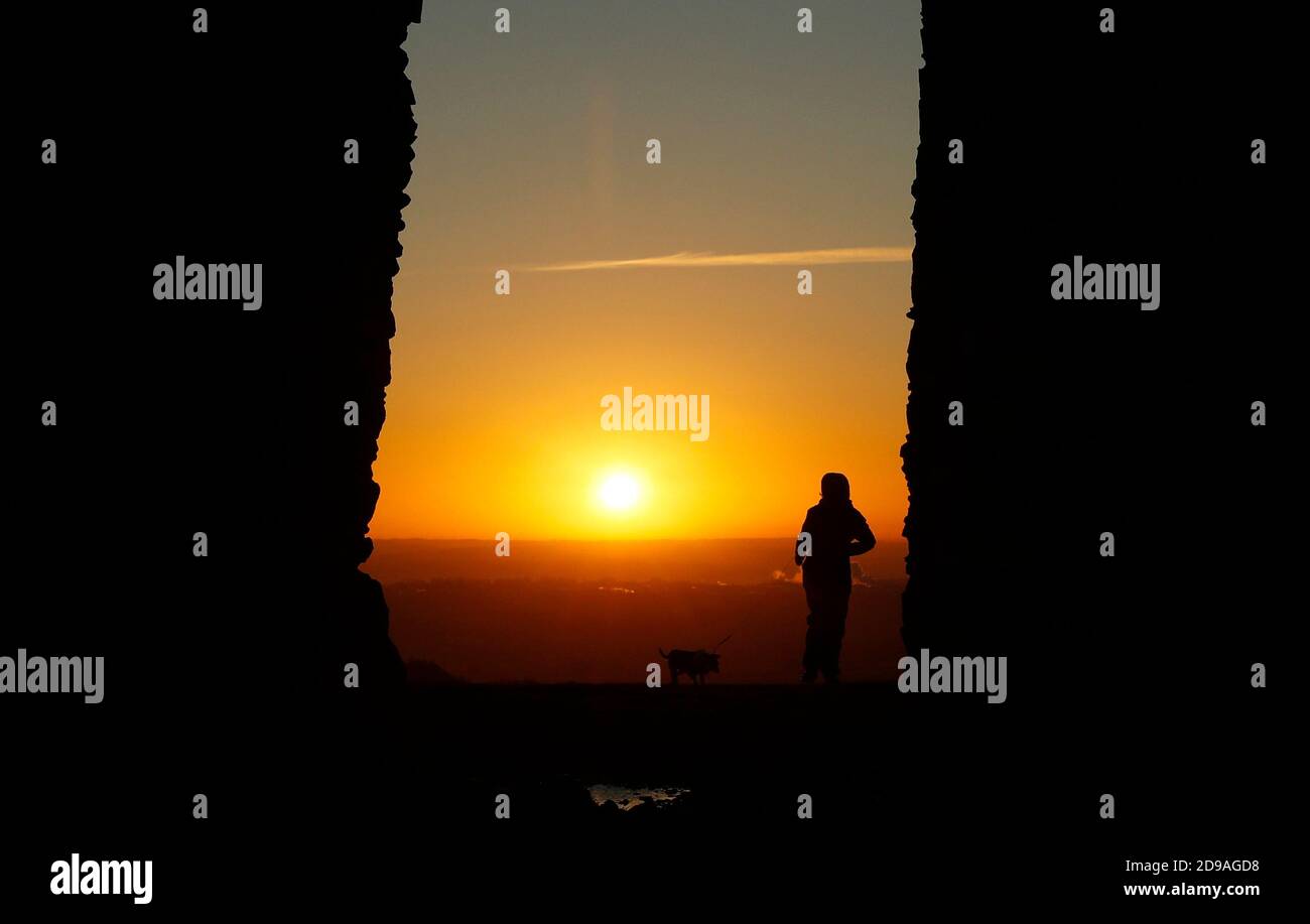 Newtown Linford, Leicestershire, Regno Unito. 4 novembre 2020. Meteo nel Regno Unito. Un camminatore di cani passa per Old John durante l'alba nel Bradgate Park. Credit Darren Staples/Alamy Live News. Foto Stock