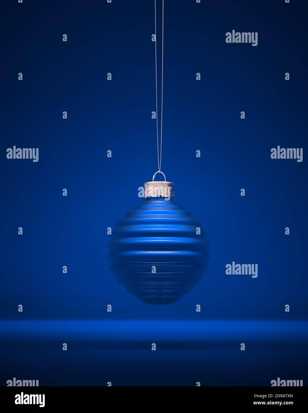 Palla di Natale blu a coste orizzontali. Bauble contro sfondo blu reale ombreggiato. Decorazione di Natale, concetto di atmosfera festosa. Foto Stock