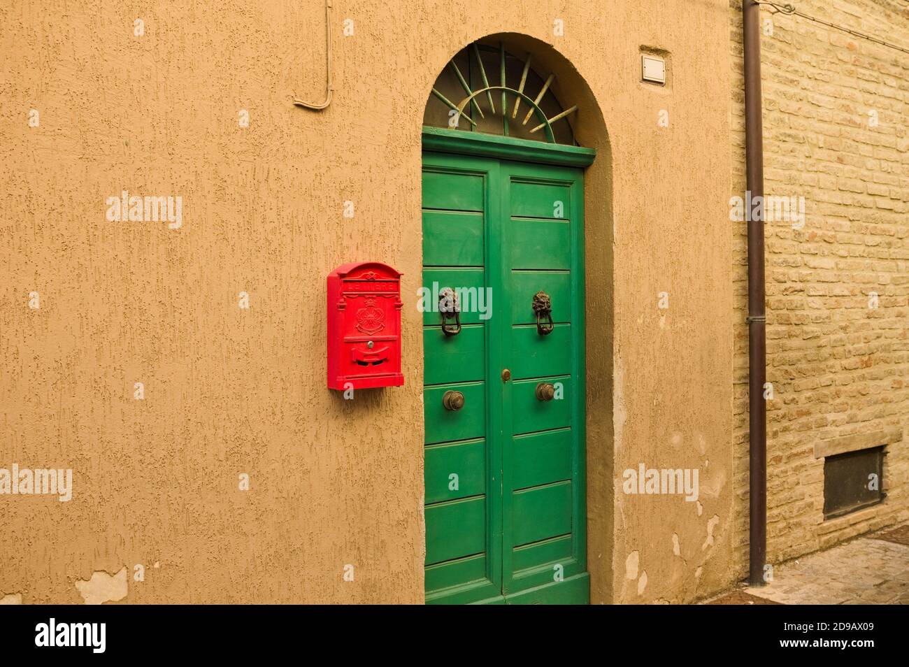 Casella postale rossa appesa alla parete di una casa con porta verde ("lettere" significa lettere in lingua italiana) (Corinaldo, Marche, Italia) Foto Stock