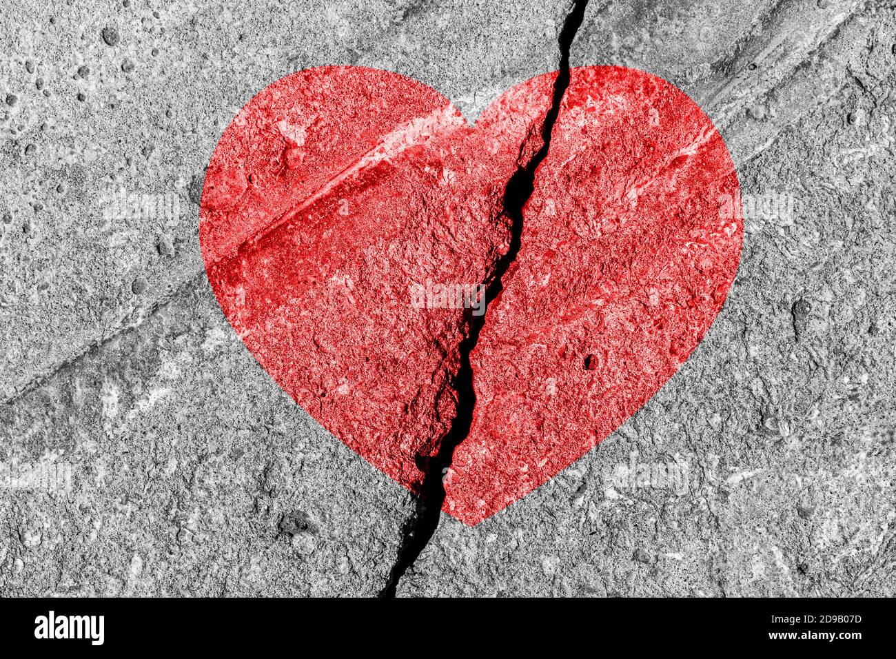Cuore rosso su una consistenza incrinata. Il concetto di cuore spezzato, fine dell'amore e delusione. Foto Stock