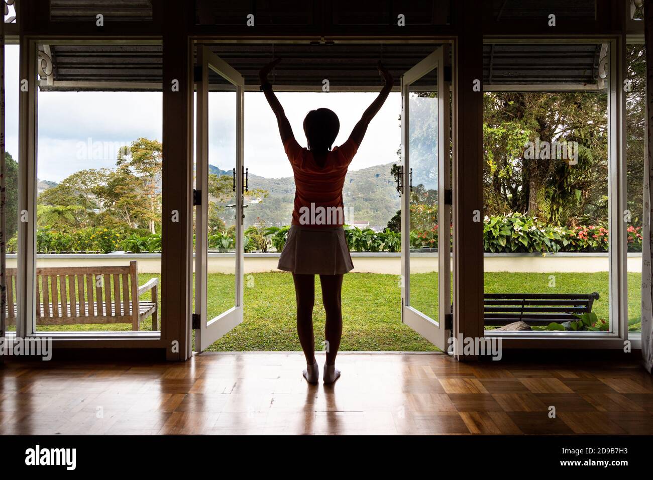 Le donne godono di un'alba rinfrescante con una scena verde dall'interno di casa Foto Stock