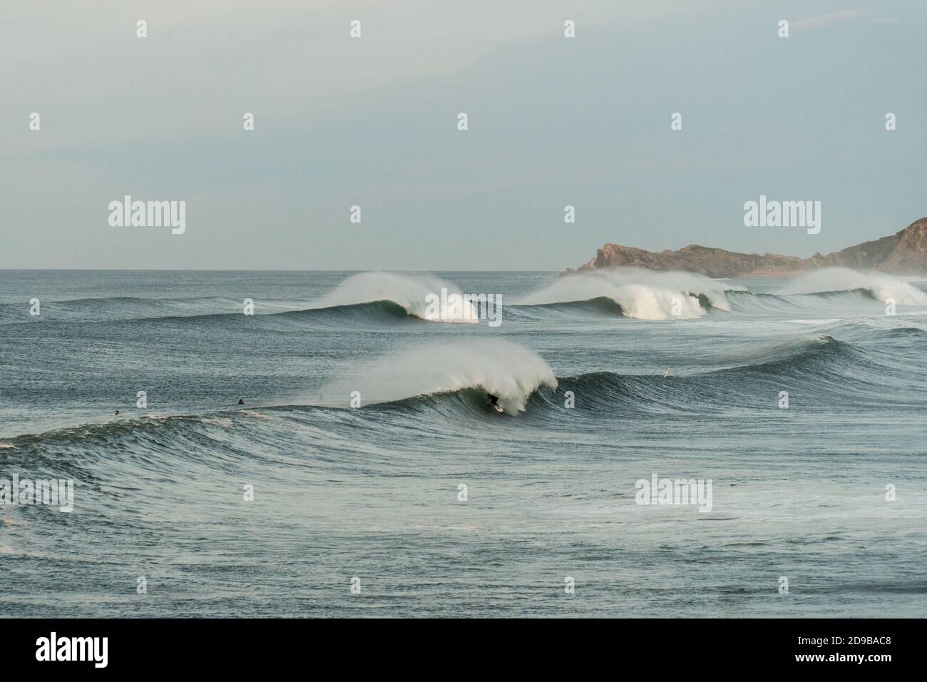 Perfetto luogo di surf con alcuni surfisti e una moto d'acqua in una bella serata d'autunno a Cantabria, nel nord della Spagna Foto Stock