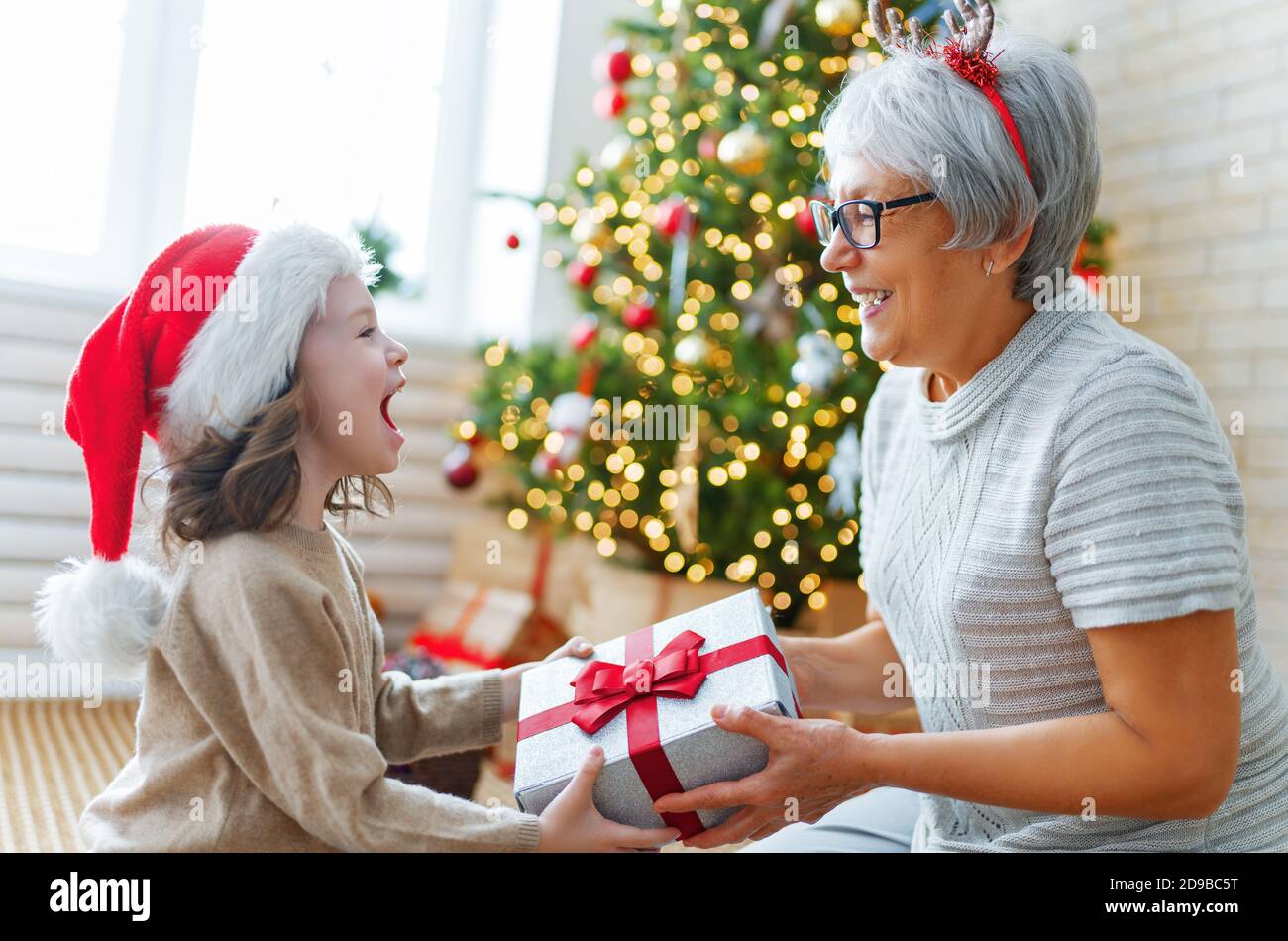 Buon Natale e buone feste! Nonna allegra e la sua bella figlia grande  ragazza scambio di doni. Granny e bambino piccolo che si diverte vicino  albero i Foto stock - Alamy