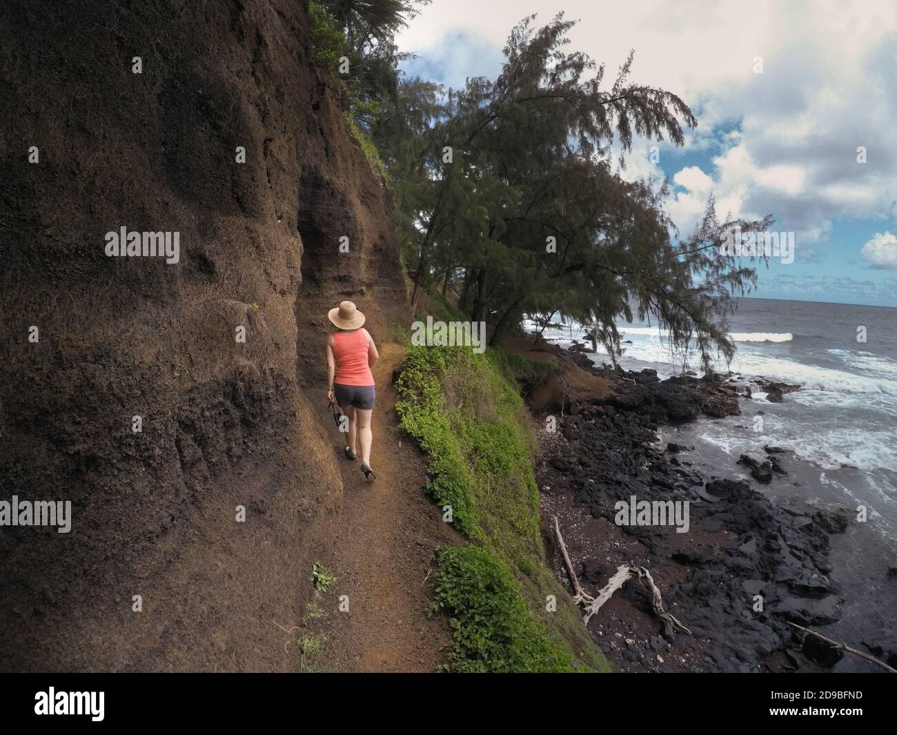 Vista posteriore di un Hiker femminile camminando lungo il sentiero costiero verso Red Sand Beach, Maui, Hawaii, USA Foto Stock